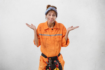 Female carpenter having doubts while can`t decide what is reason of breakdown, posing against white...