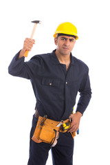 Happy beard worker smiling and hitting with a hammer, guy wearing dark blue workwear and belt equipment with yellow helmet, isolated on white background