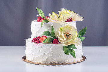 Home wedding two-tiered cake decorated with currants, strawberries and yellow flowers. Festive berry dessert