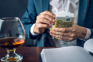 Man Businessman in suit puts money in his pocket. A bribe in the form of Euro bills. Concept of corruption and bribery