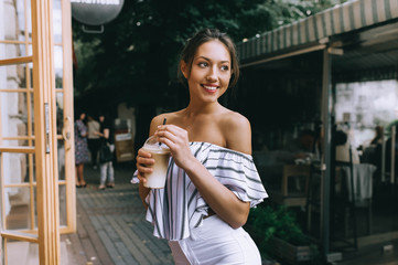 beautiful young girl drinking coffee in the city