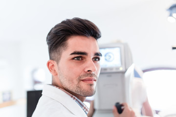 Male optometrist checking patient's vision at eye clinic. Medical examination.