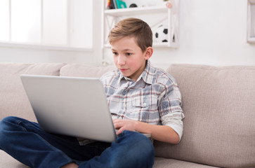 Teenage boy using laptop on couch at home