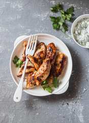 Yogurt marinated grilled chicken breast on a gray background, top view