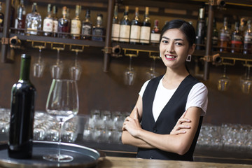Young Asian Woman Waiter Restaurant Catering Service Happy Emotion. Woman Waiter Present Red-Wine for Customer at Bar. Woman with Wine in Bar Concept.