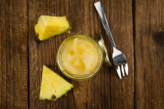 Portion of Chopped Pineapple (preserved) on wooden background, selective focus