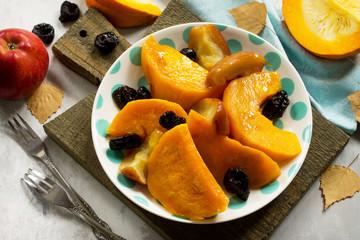 Pumpkin baked with apples, prunes and spices in a bowl on a stone background.