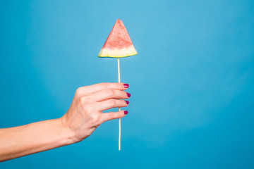 Female hand holding a piece of watermelon on a stick. Summer, holiday, fruit and people concept
