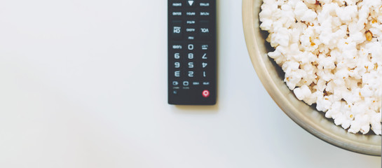 TV remote control with big bowl of popcorn
