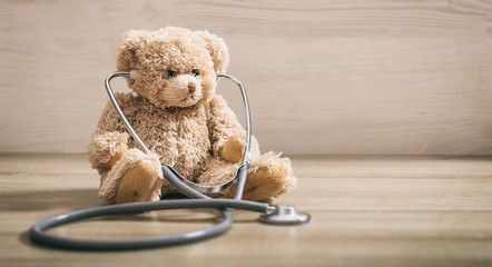 Teddy bear and a stethoscope on a wooden floor