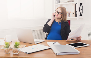Obraz premium Pregnant business woman talking on phone at office