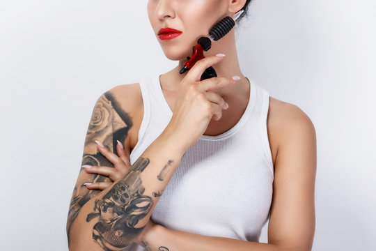 Young woman tattooist with a tattoo-machine in her hand