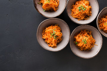 Set of plates with russian korean salad on black background
