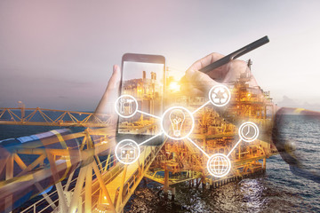 Double exposure photo, hand touching mobile phone for using business tool icons,with oil & gas platform  background for industrial concept