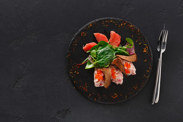 Gourmet seafood snack on black plate top view