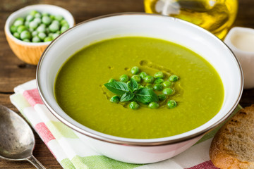 Green pea soup in bowl on wooden table