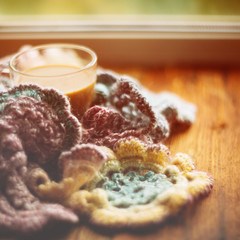 Coffee with milk wrapped in warm white knitted scarf and flowers tagetes on white wooden table. Mood of warmth and comfort. Seasonal autumn concept. Square image