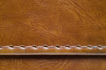 Texture of brown leather with stitches. Element of leather clothing close-up. Seams on leather products