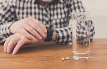 Senior man hands with glass of water and pills