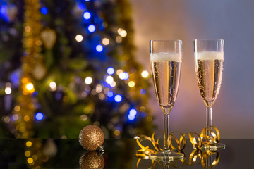 Two glasses of champagne on the table and background of a blurred  decorated Christmas tree