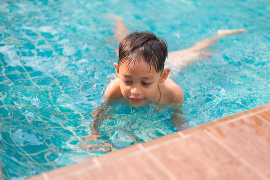 Little asian boy having fun in the pool during summer time.