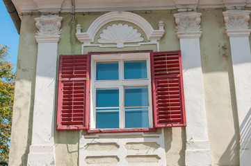 Fototapeta na wymiar Old red window on the historical building.