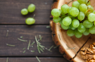Grapes on natural wood disc with herbs and nuts