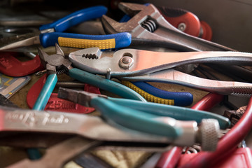 Set of pliers, wrench and other tool supplies for technician in drawer / toolbox. Closeup view of cupboard / box with stainless steel hardware for carpentry work
