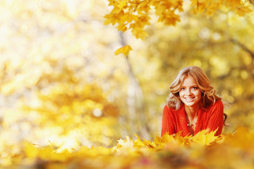 Naklejka na ściany i meble Woman laying on autumn leaves