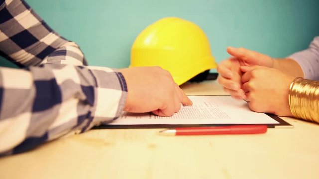 Woman signing construction contract with contractor to build a house