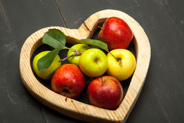 Apples in the heart on a black wooden background