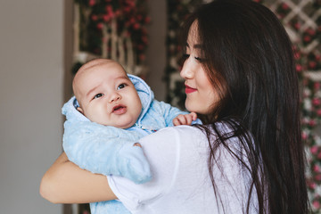 Loving Asian Mother Holding Baby Son At Home