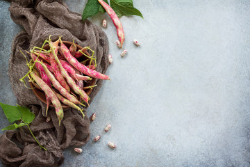 A pod of green beans and beans. Red beans on a gray slate or stone background. Top view with copy space.