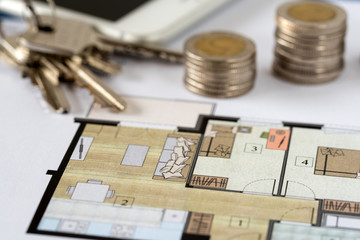 Coins and keys with home on architectural drawings of the modern house.