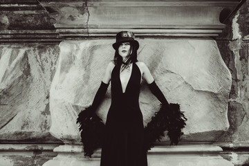 Gothic lady in a luxurious glamorous retro look for Halloween. Beautiful citizen in vintage clothing with feathers and fine accessories of handmade work. Ideas for the  Halloween holiday