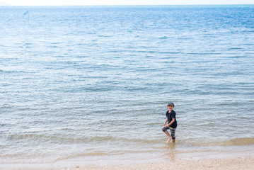 Fototapeta na wymiar Happy asian boy playing and walking at the beach