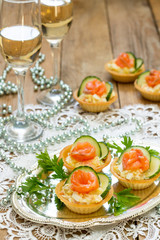 Christmas snack on the festive table. Tartlets with salad, decoration from salmon and cucumber.