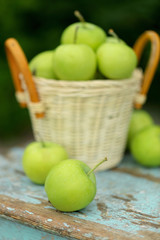Homemade rustic green apples in a basket on an old stool.
