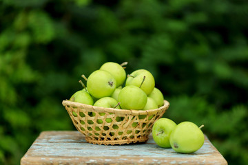 Homemade rustic green apples in a basket on an old stool.