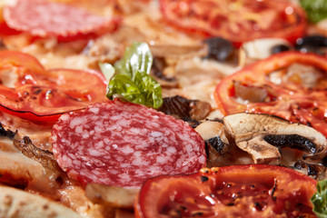 Obraz premium Closeup of pizza with salami, tomatoes and olives