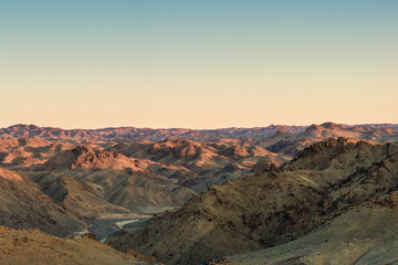Naklejka premium picturesque landscape of pine forest stretching to foot of great snow-covered mountains at sunny day 