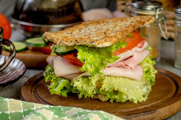 Sandwich with ham, cucumber, tomato and lettuce.