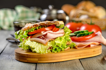 Sandwich with ham, cucumber, tomato and lettuce.