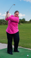 Golfspielerin beim Abschlag auf einem Golfplatz