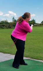Golfspielerin beim Abschlag auf einem Golfplatz