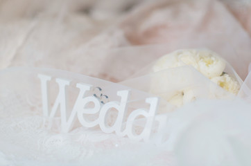белая деревянная табличка с надписью свадьба лежит на платье невесты 