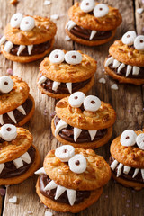 Halloween food: monsters of nutty cookies with chocolate cream close-up. vertical