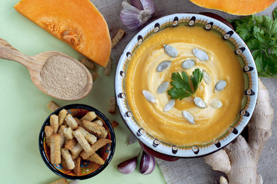 Pumpkin cream soup with crackers and ginger, parsley and  seeds. Top view