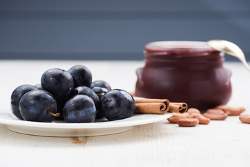 Raw organic plums, jam, raw cocoa beans and cinnamon on white background side view
