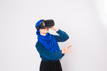 Asian muslim woman wearing hijab using VR headset glasses of virtual reality on white background.